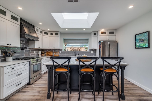 kitchen with a center island, decorative backsplash, appliances with stainless steel finishes, and a breakfast bar area