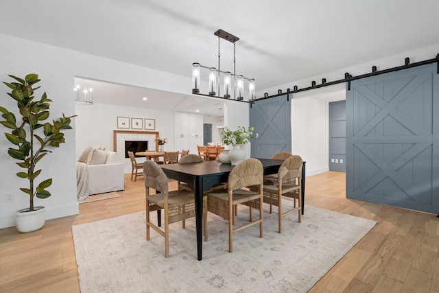 dining room featuring a barn door, baseboards, light wood finished floors, and a fireplace