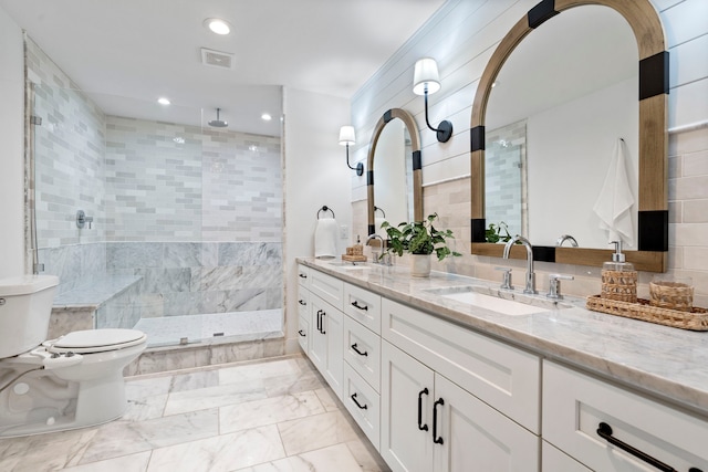 full bath with visible vents, a sink, a tile shower, and toilet
