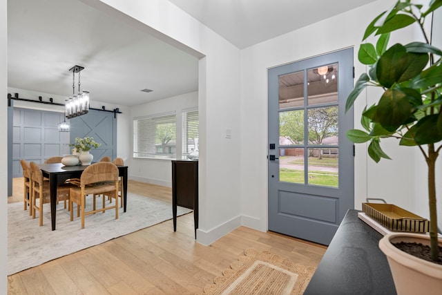 entrance foyer featuring a barn door, baseboards, visible vents, and light wood-type flooring