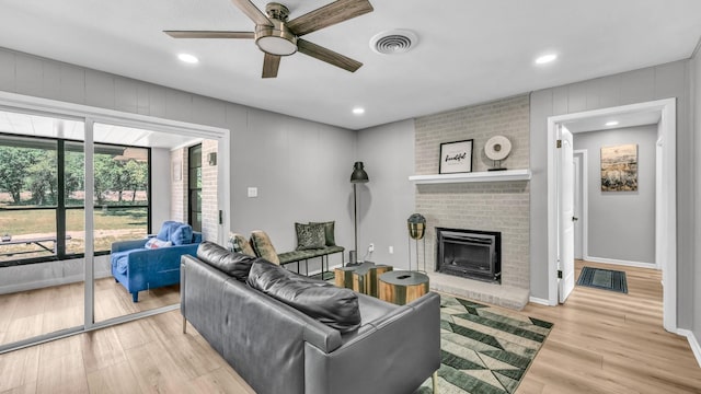 living room featuring a ceiling fan, visible vents, a brick fireplace, wood finished floors, and recessed lighting