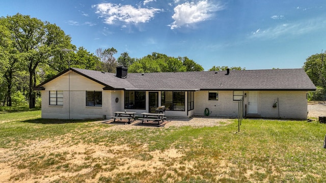 back of house with a yard, a patio, a chimney, and brick siding