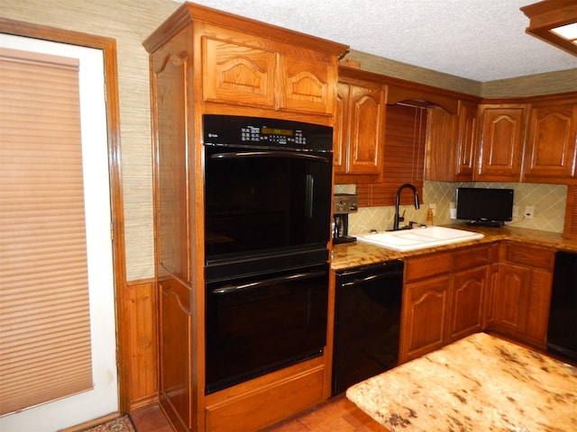 kitchen featuring decorative backsplash, a sink, brown cabinetry, and black appliances