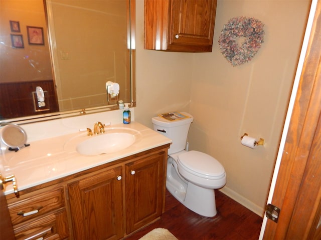 bathroom featuring baseboards, wood finished floors, toilet, and vanity