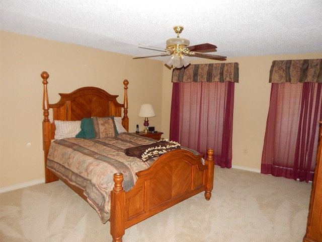 bedroom with baseboards, a textured ceiling, light colored carpet, and ceiling fan