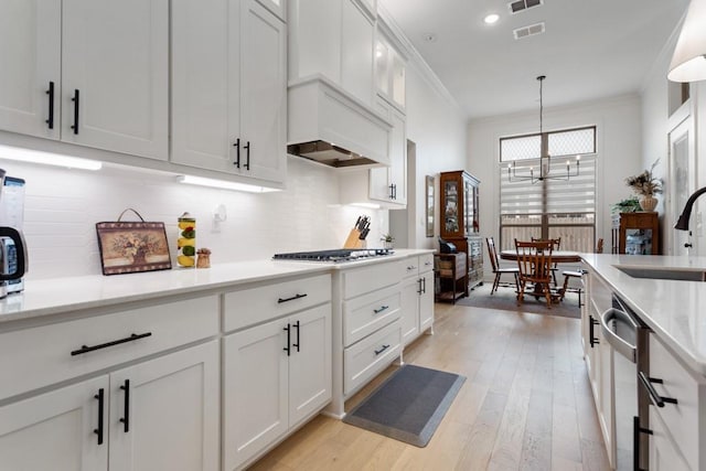 kitchen featuring light wood-style flooring, a sink, tasteful backsplash, visible vents, and appliances with stainless steel finishes