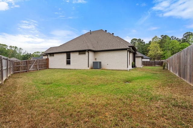 rear view of house featuring a fenced backyard, brick siding, a yard, and central air condition unit