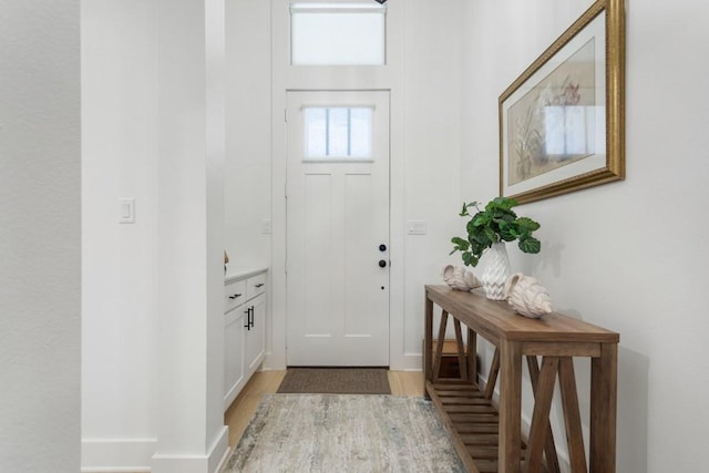 foyer entrance with baseboards and light wood-style flooring