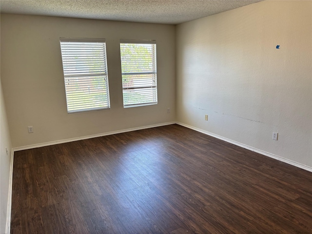 unfurnished room with dark wood finished floors, a textured ceiling, and baseboards