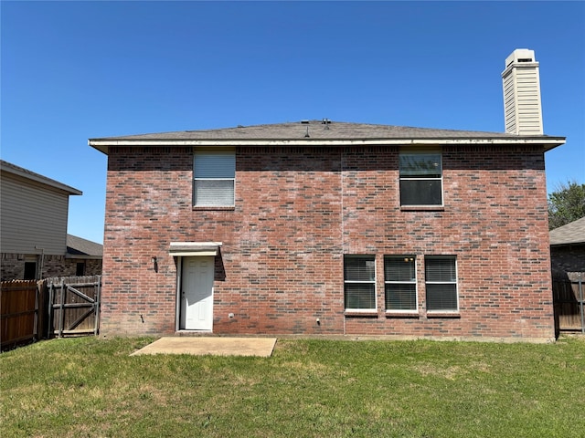 back of house with a lawn and brick siding