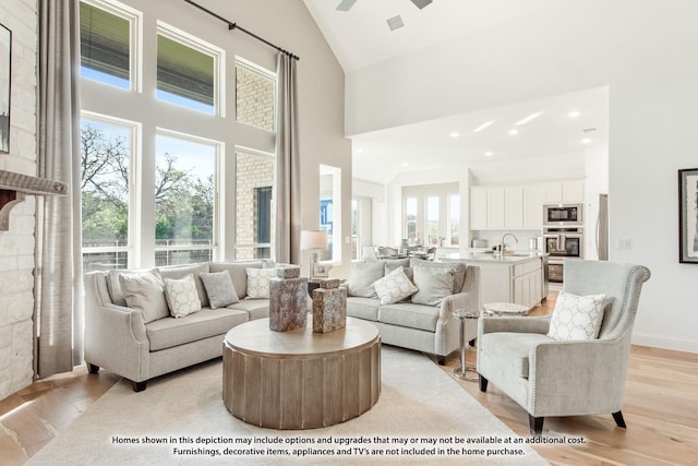 living room with light wood finished floors, visible vents, high vaulted ceiling, and recessed lighting
