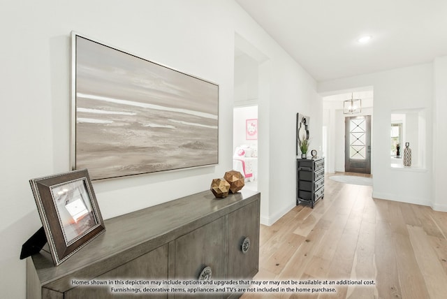 entrance foyer with light wood-style flooring, baseboards, and a notable chandelier