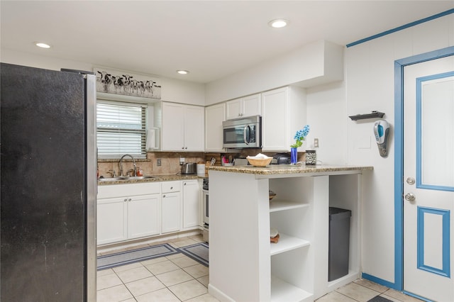 kitchen featuring white cabinetry, light tile patterned floors, stainless steel appliances, and a sink