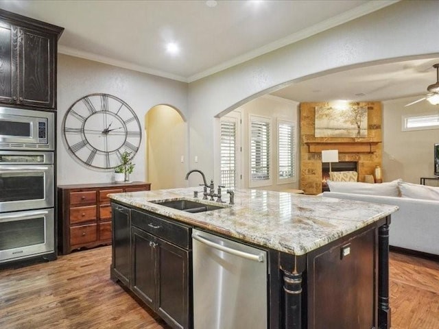 kitchen with ornamental molding, a sink, arched walkways, appliances with stainless steel finishes, and open floor plan