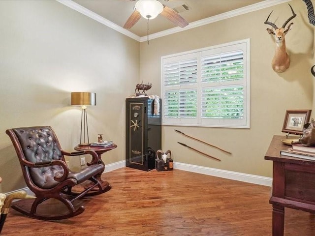 sitting room featuring visible vents, baseboards, a ceiling fan, wood finished floors, and crown molding