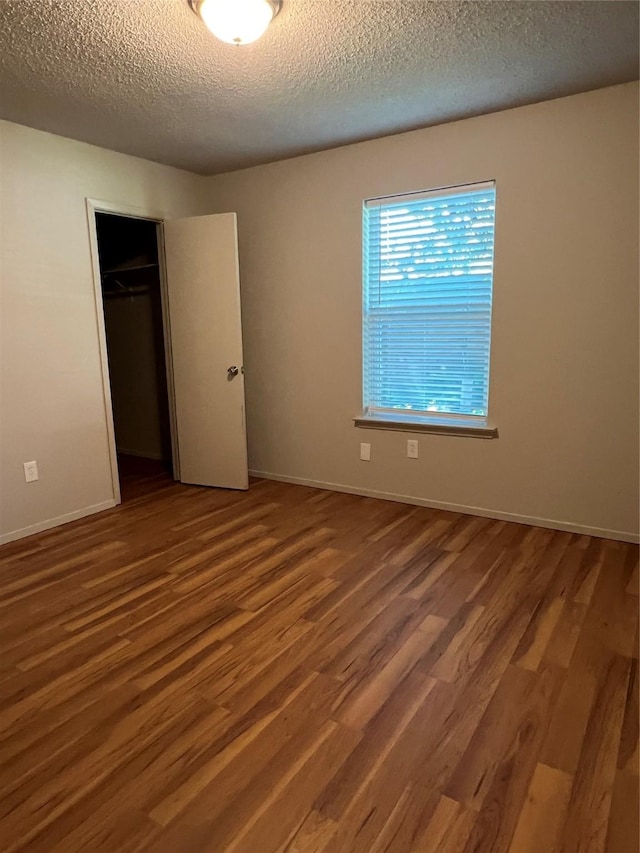 800 Woodland Ct, Kennedale, TX 76060 - unfurnished bedroom with a closet, wood finished floors, a textured ceiling, and baseboards