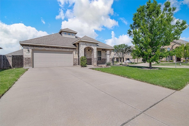 view of front of home with fence, concrete driveway, brick siding, a front yard, and a garage