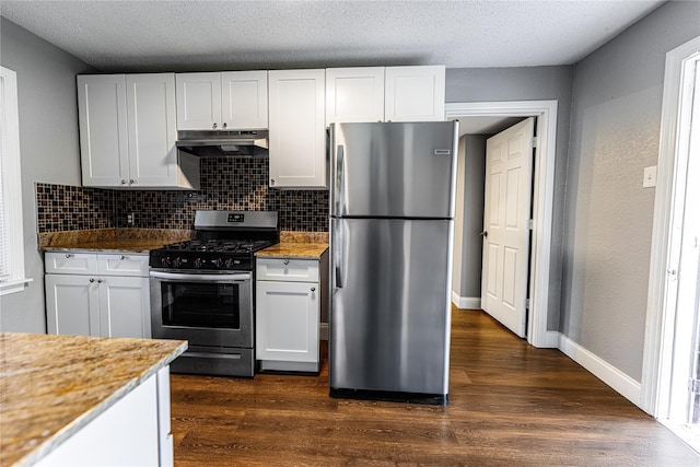 3143 Grayson Dr, Dallas, TX 75224 - kitchen with appliances with stainless steel finishes, under cabinet range hood, dark wood-style flooring, tasteful backsplash, and white cabinets