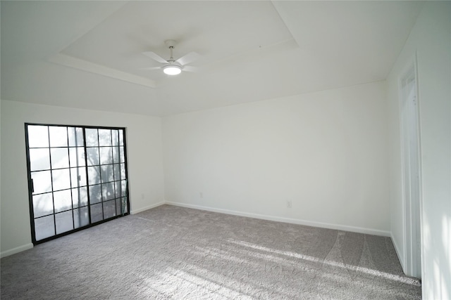 carpeted empty room with baseboards, a ceiling fan, and a tray ceiling