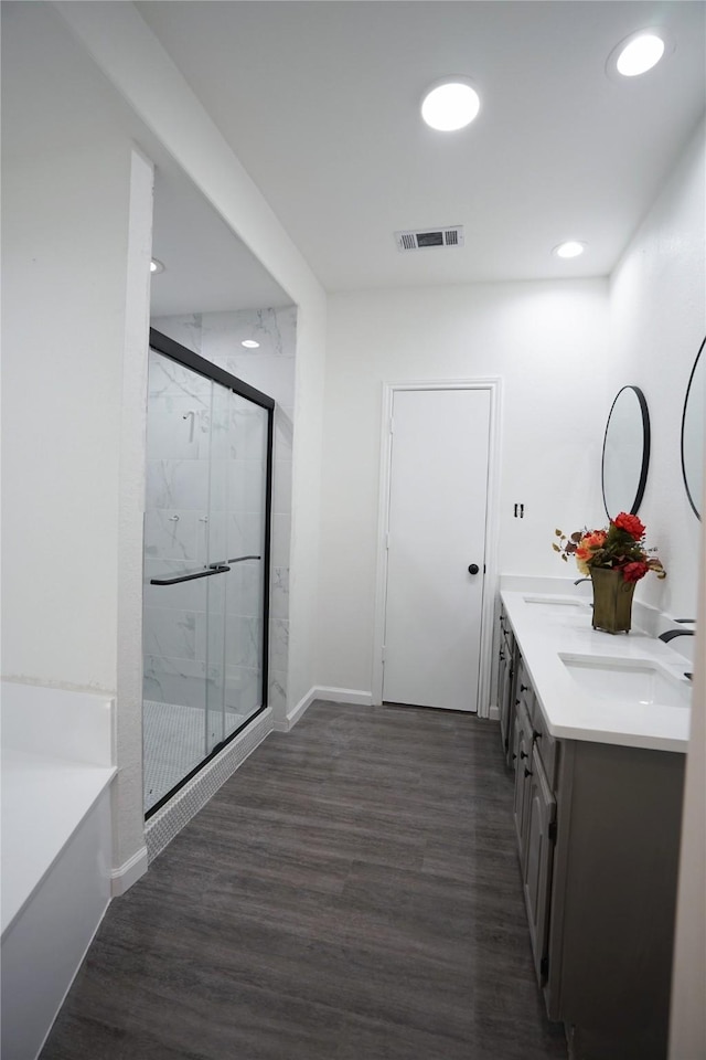 full bathroom featuring a marble finish shower, a sink, baseboards, visible vents, and wood finished floors