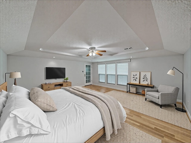907 Red Oak Creek Dr, Ovilla, TX 75154 - bedroom with a tray ceiling, a textured ceiling, wood finished floors, baseboards, and a ceiling fan