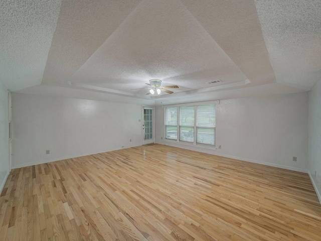 907 Red Oak Creek Dr, Ovilla, TX 75154 - empty room featuring a textured ceiling, a ceiling fan, light wood-style flooring, a tray ceiling, and baseboards