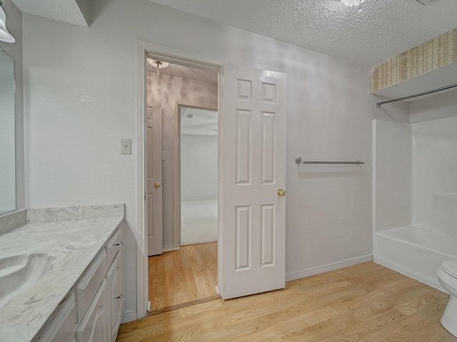 907 Red Oak Creek Dr, Ovilla, TX 75154 - full bathroom with wood finished floors, a textured ceiling, vanity, toilet, and shower / washtub combination