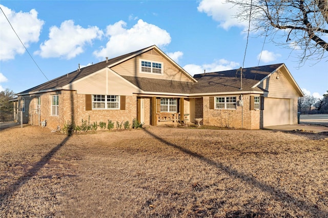 view of front of home with brick siding, an attached garage, a porch, and driveway
