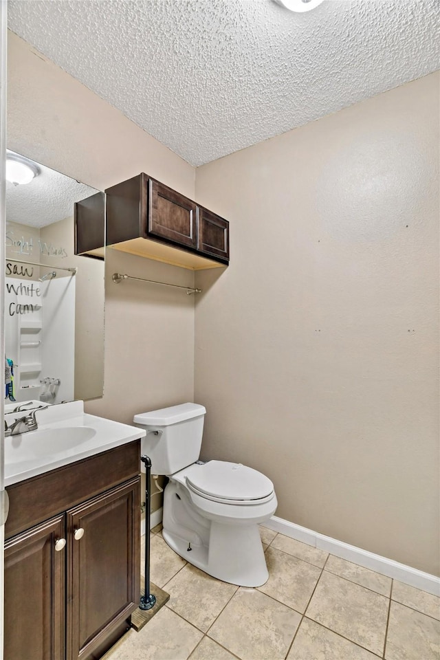 bathroom featuring a textured ceiling, vanity, baseboards, toilet, and tile patterned flooring