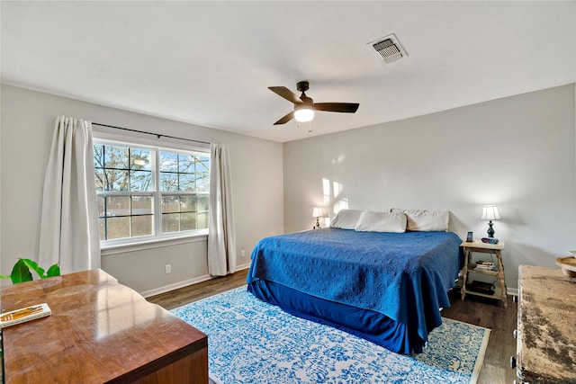 bedroom featuring baseboards, visible vents, ceiling fan, and dark wood finished floors