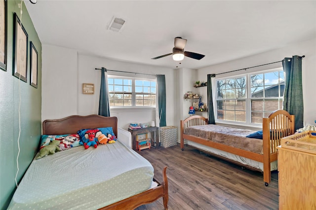 bedroom featuring wood finished floors, visible vents, a ceiling fan, and baseboards