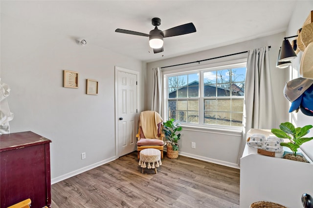 living area with baseboards, a ceiling fan, and wood finished floors