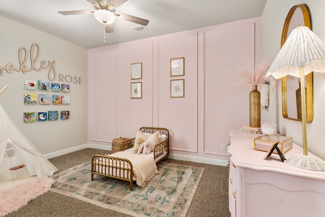 carpeted bedroom with visible vents, a decorative wall, and a ceiling fan