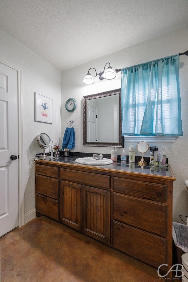 bathroom with a textured wall, vanity, and finished concrete floors