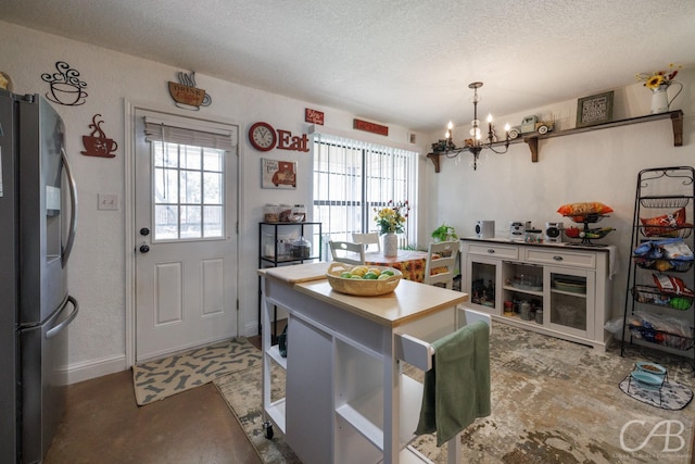kitchen featuring an inviting chandelier, a textured ceiling, plenty of natural light, and stainless steel fridge with ice dispenser