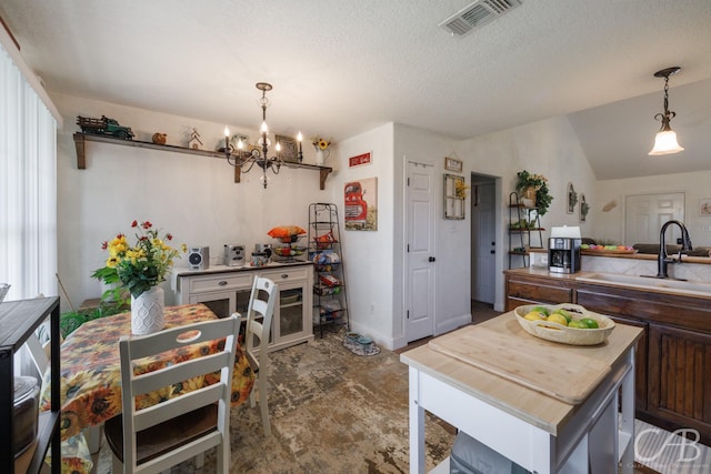 kitchen with a sink, vaulted ceiling, visible vents, a notable chandelier, and pendant lighting