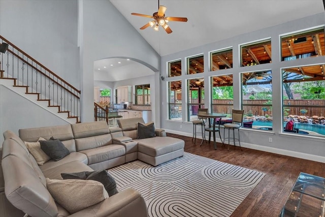 living room featuring high vaulted ceiling, a ceiling fan, wood finished floors, arched walkways, and baseboards