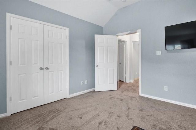 unfurnished bedroom featuring baseboards, lofted ceiling, a closet, and carpet