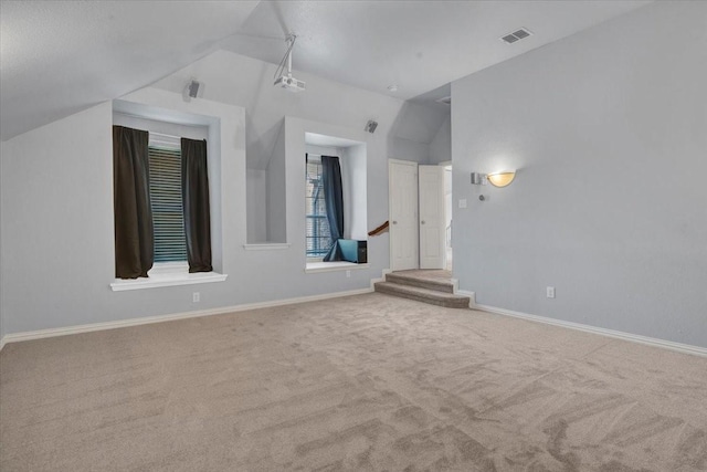 interior space with baseboards, lofted ceiling, visible vents, and carpet