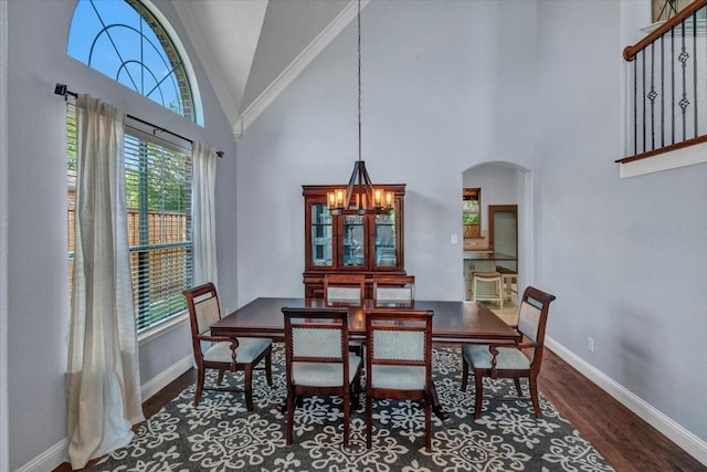dining area featuring arched walkways, baseboards, an inviting chandelier, wood finished floors, and high vaulted ceiling