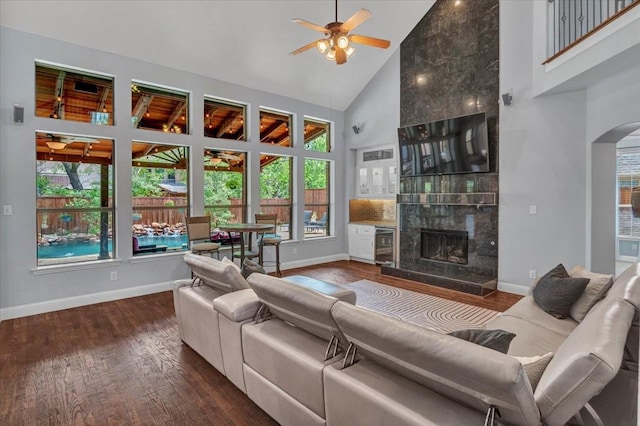 living area with baseboards, a ceiling fan, wood finished floors, and high vaulted ceiling