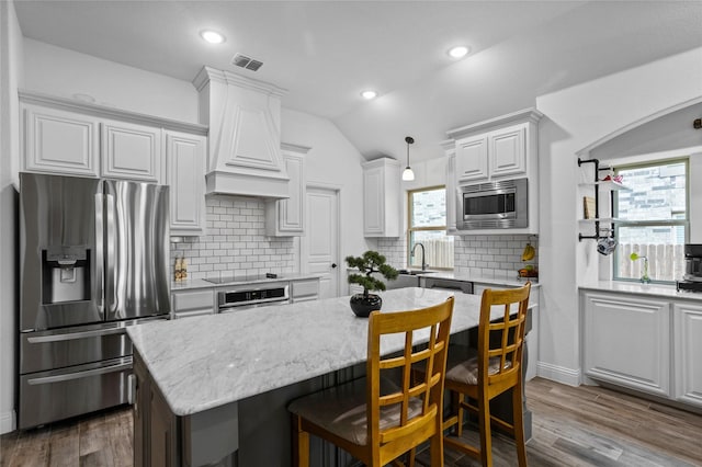 kitchen featuring lofted ceiling, visible vents, tasteful backsplash, appliances with stainless steel finishes, and custom exhaust hood