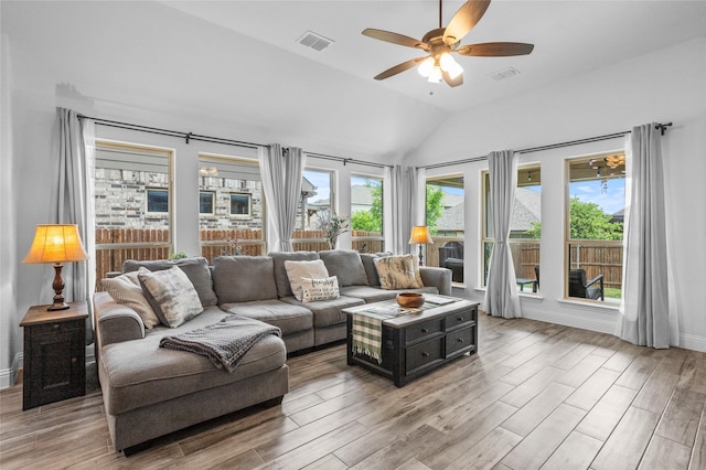 living area with lofted ceiling, light wood finished floors, visible vents, a ceiling fan, and baseboards