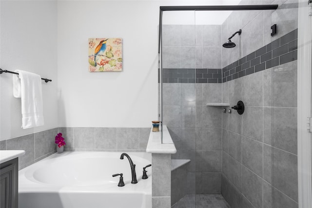 bathroom with a shower stall, a bath, and vanity