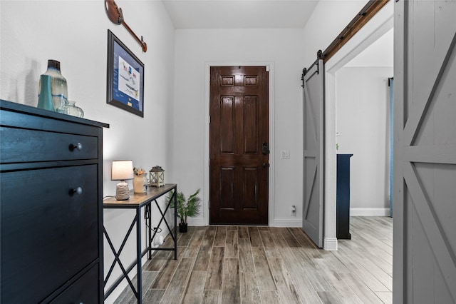 foyer featuring light wood-style flooring, baseboards, and a barn door