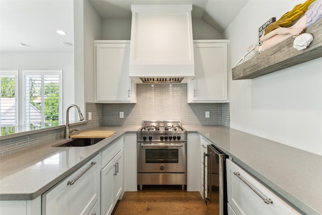 kitchen with white cabinets, wine cooler, high end stove, a sink, and custom range hood