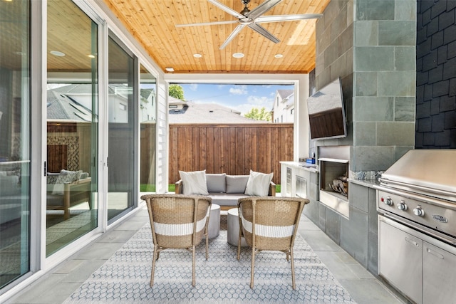view of patio / terrace with fence, a ceiling fan, and exterior kitchen