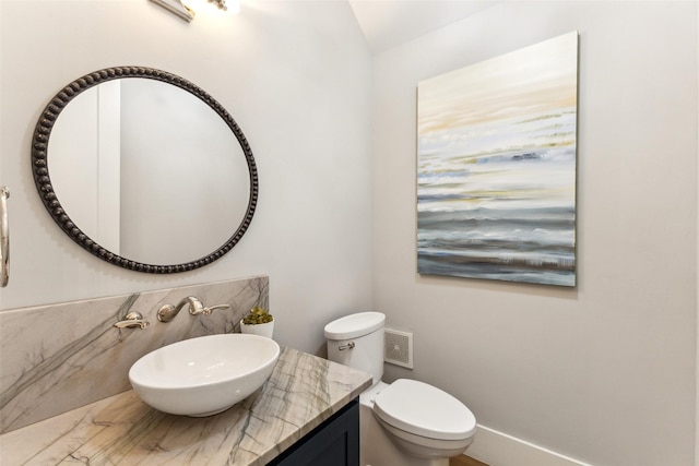 half bathroom featuring vaulted ceiling, toilet, and vanity