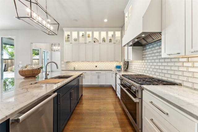 kitchen with white cabinets, a sink, a chandelier, custom range hood, and appliances with stainless steel finishes