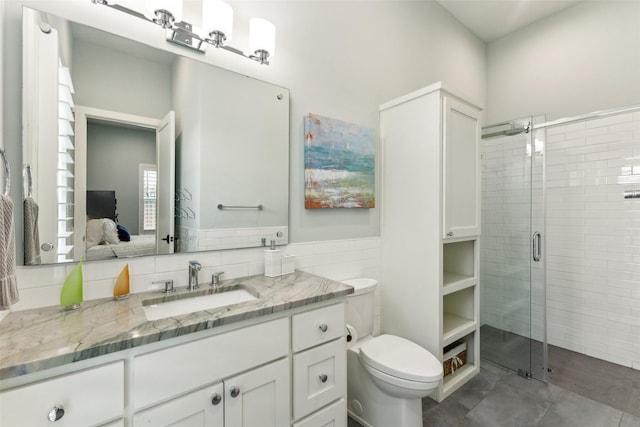 bathroom with a shower stall, vanity, toilet, and tile walls